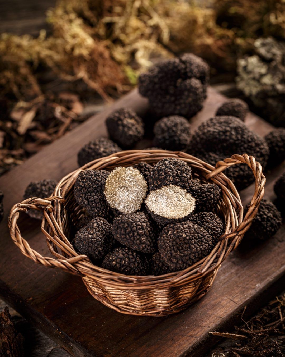 Basket with black truffles on dark wooden board