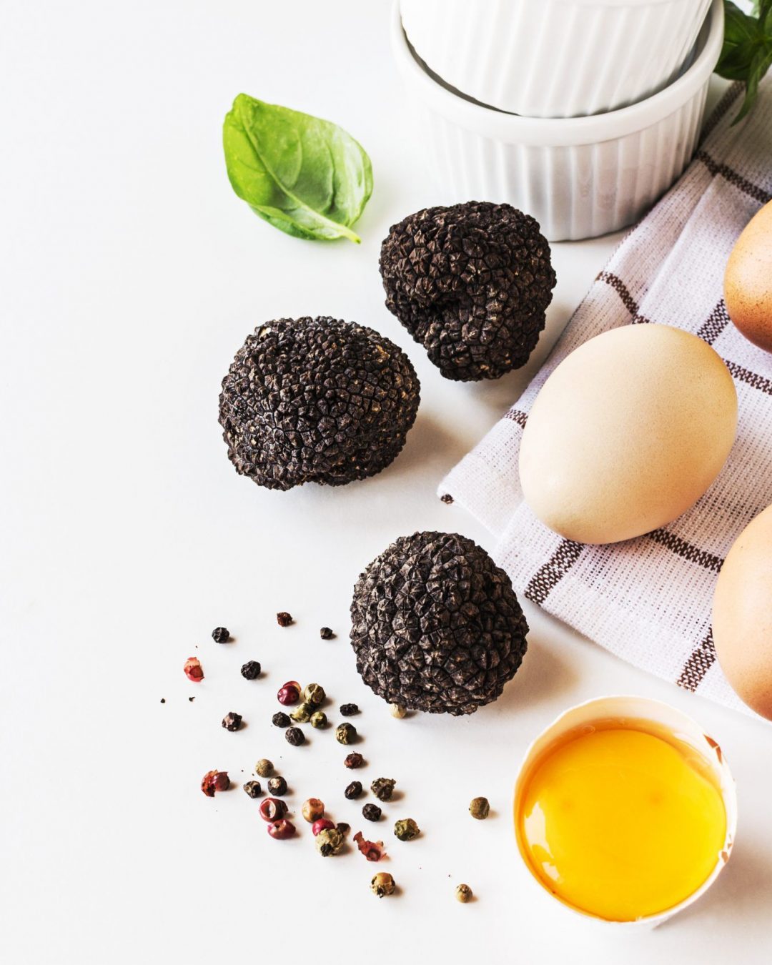 Ingredients for omelette with black trufflies on white table.